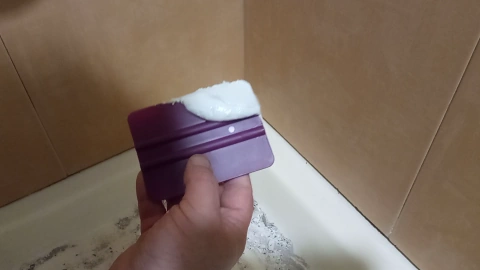 Sellando la junta de la bañera con cemento blanco